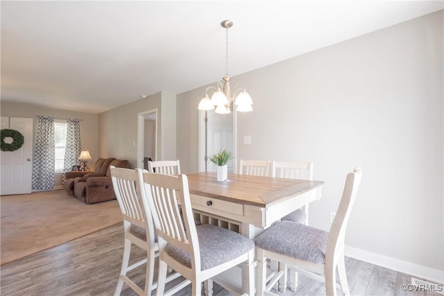 dining area with light wood-style flooring, a chandelier, and baseboards