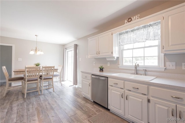 kitchen featuring a notable chandelier, stainless steel dishwasher, light countertops, and a sink