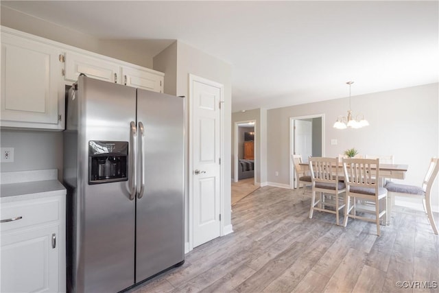 kitchen featuring an inviting chandelier, light wood-style flooring, white cabinets, baseboards, and stainless steel refrigerator with ice dispenser
