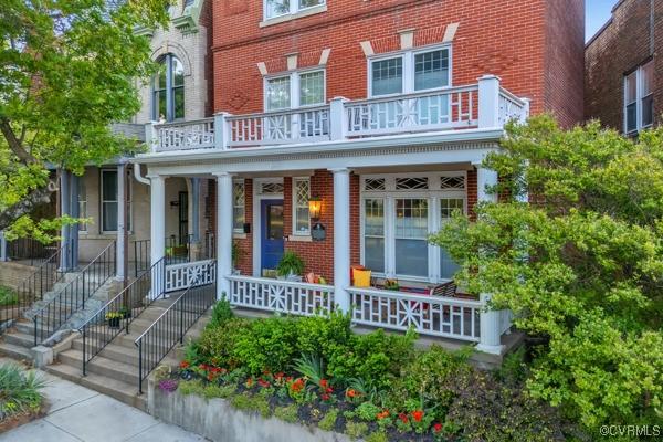 doorway to property featuring a porch, a balcony, and brick siding