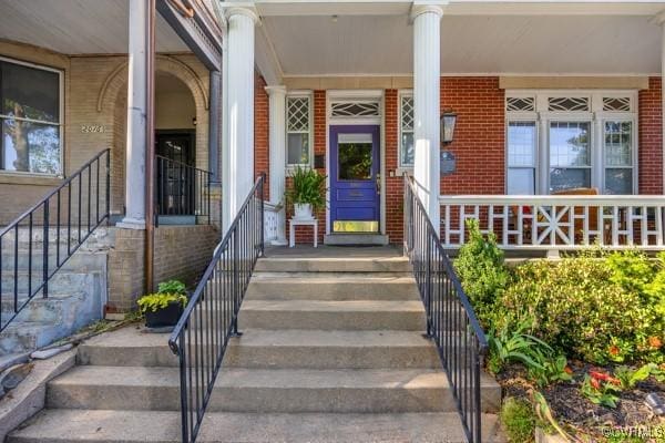 property entrance featuring a porch and brick siding