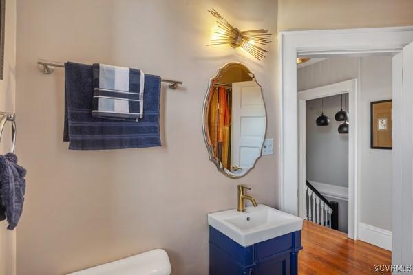 half bath featuring vanity, baseboards, and toilet