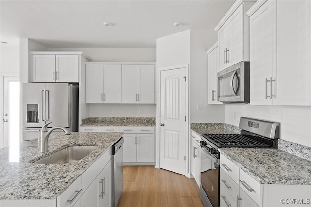 kitchen with stainless steel appliances, white cabinetry, and a sink