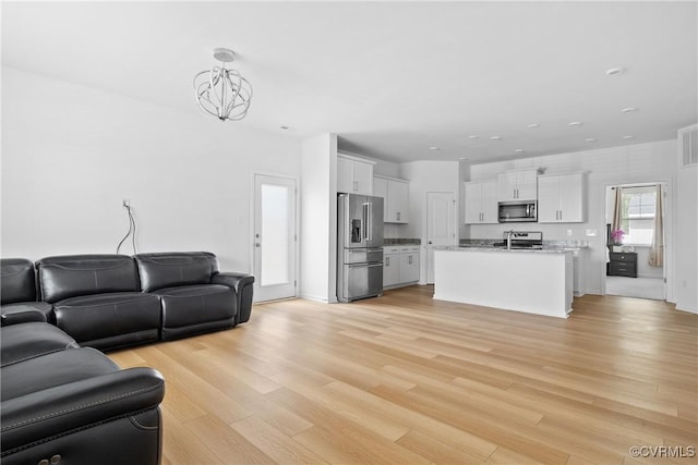 living room with recessed lighting, visible vents, light wood finished floors, and a notable chandelier