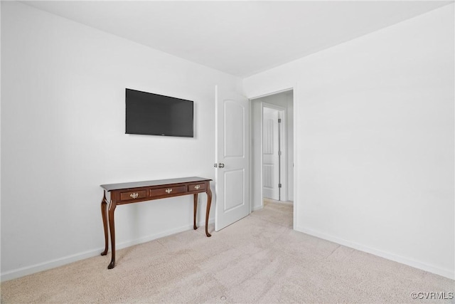 spare room featuring light colored carpet and baseboards