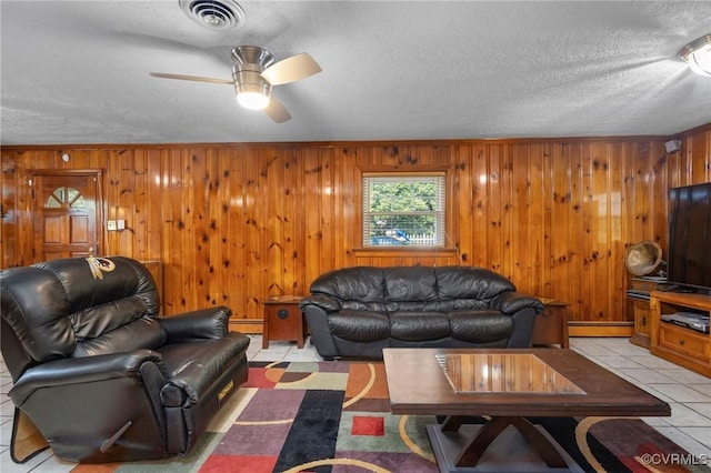 living room featuring visible vents, a baseboard heating unit, a textured ceiling, and wood walls