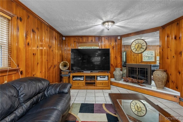 living area featuring light tile patterned floors, crown molding, a textured ceiling, and wood walls