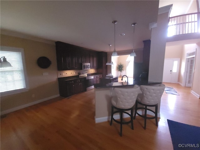 8313 Kalliope Ct, Chesterfield, VA 23838 - kitchen featuring appliances with stainless steel finishes, light wood finished floors, a breakfast bar area, a peninsula, and decorative light fixtures