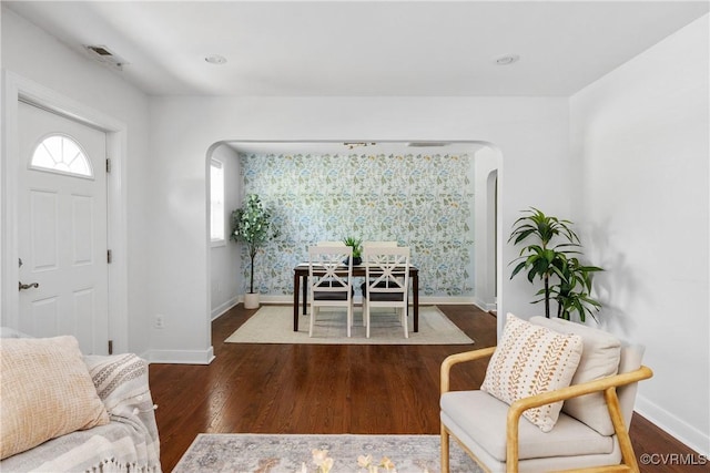 interior space with visible vents, arched walkways, baseboards, and wood finished floors