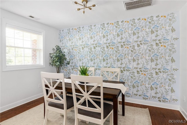 dining space with baseboards, visible vents, wallpapered walls, and wood finished floors