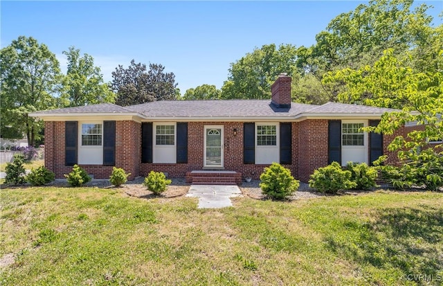 ranch-style house with brick siding, a chimney, and a front lawn