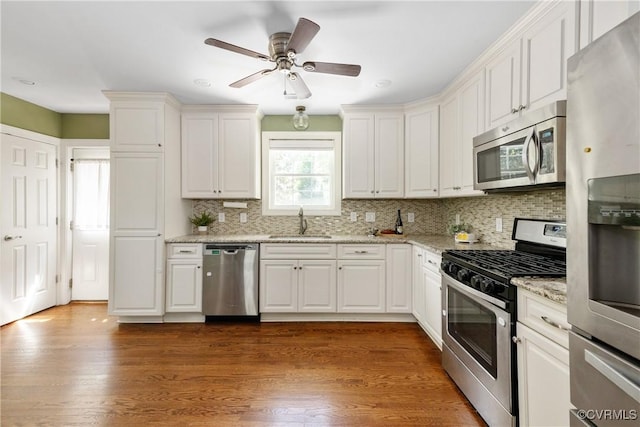 kitchen with white cabinets, appliances with stainless steel finishes, decorative backsplash, and a sink