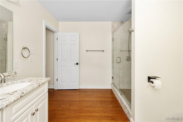 full bath with vanity, baseboards, wood finished floors, and a shower stall