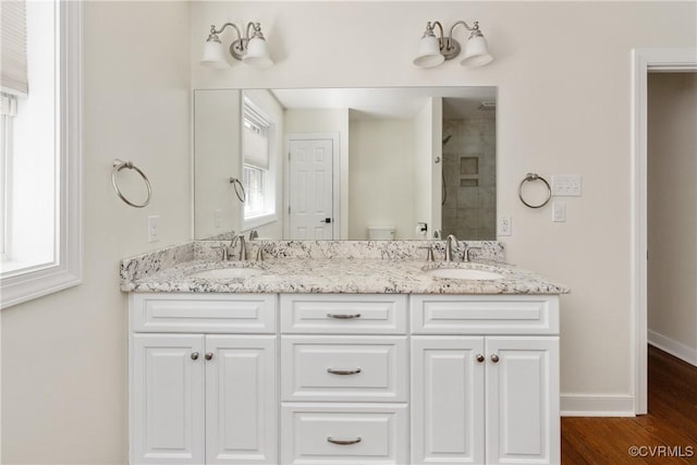 bathroom with double vanity, toilet, a sink, and wood finished floors
