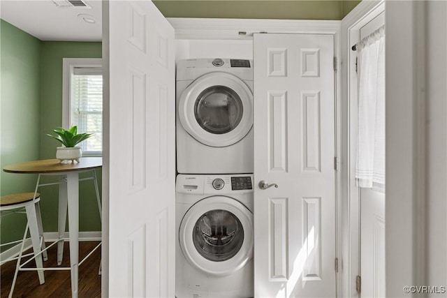laundry area featuring stacked washing maching and dryer, laundry area, and wood finished floors