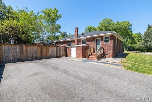 view of front facade featuring brick siding, fence, and a chimney
