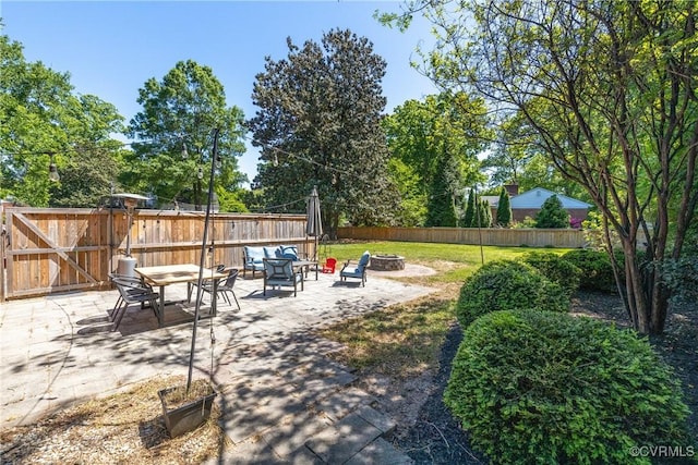 view of yard with a fenced backyard, a gate, a fire pit, and a patio area