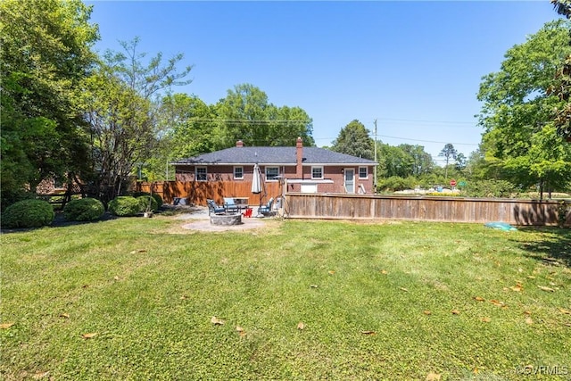 back of house featuring an outdoor fire pit, fence, a yard, and a chimney