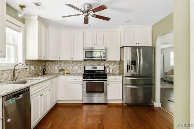 kitchen featuring ceiling fan, appliances with stainless steel finishes, a sink, arched walkways, and visible vents