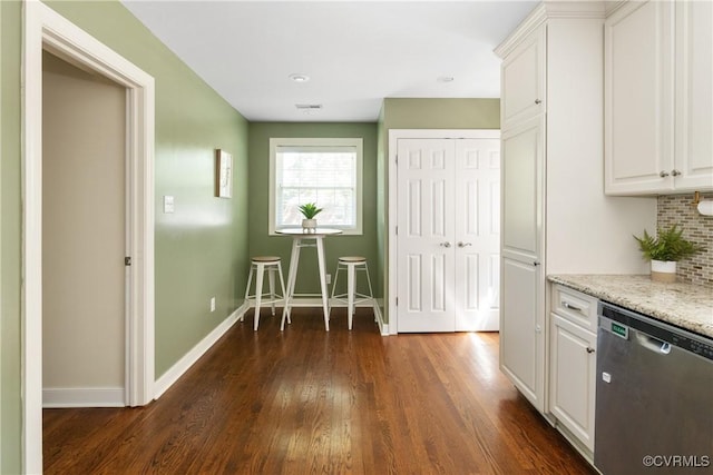 kitchen with stainless steel dishwasher, dark wood-style flooring, baseboards, and white cabinets