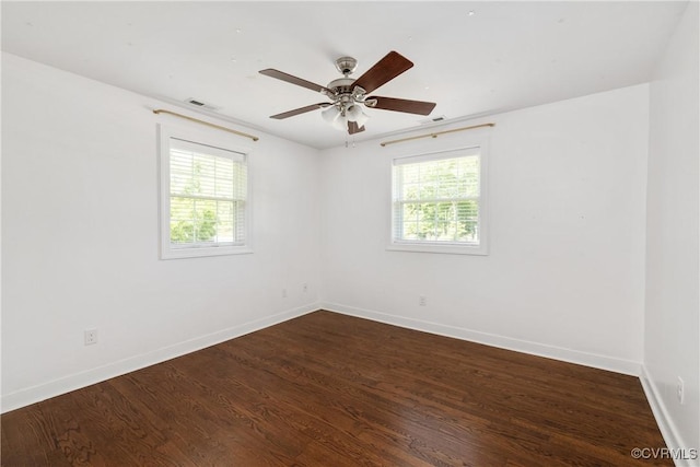 spare room with a ceiling fan, baseboards, visible vents, and dark wood finished floors
