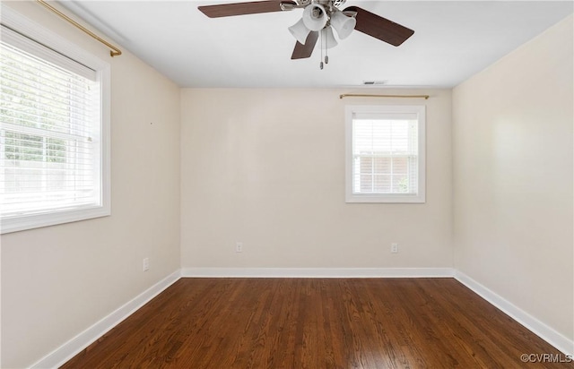 unfurnished room featuring baseboards, dark wood finished floors, ceiling fan, and visible vents