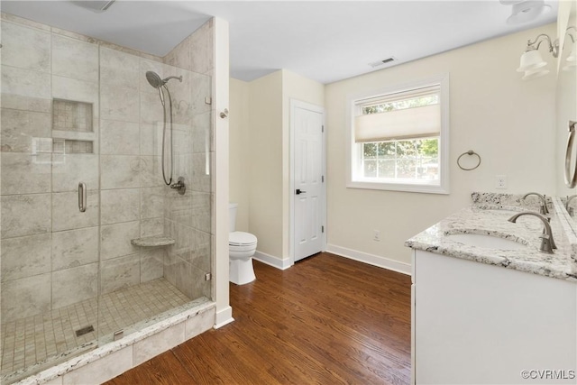 full bathroom with visible vents, wood finished floors, toilet, a shower stall, and a sink