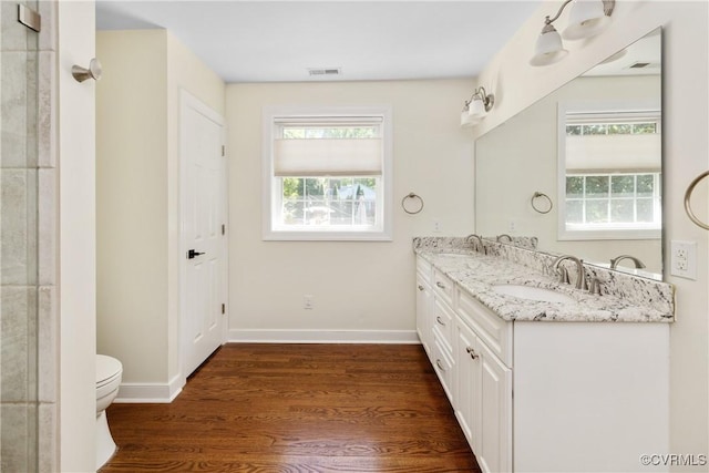 bathroom featuring visible vents, a sink, wood finished floors, and toilet