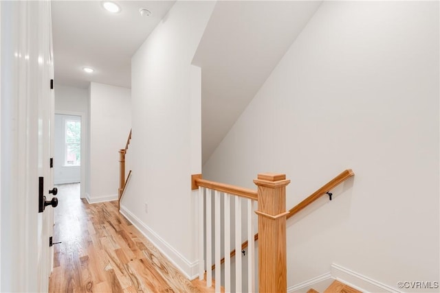 corridor featuring baseboards, recessed lighting, light wood-style flooring, and an upstairs landing
