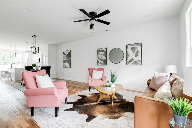 living room with light wood-style floors, baseboards, and ceiling fan