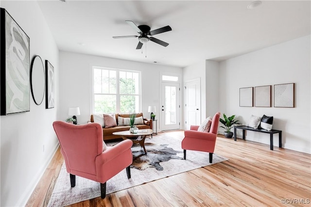 living room with baseboards, light wood-style flooring, and ceiling fan
