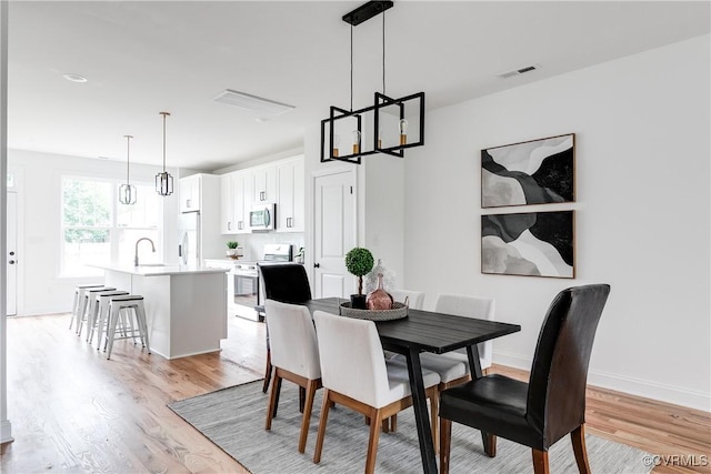 dining space featuring visible vents, light wood finished floors, and baseboards