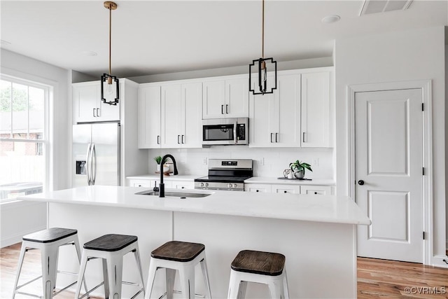 kitchen with a sink, stainless steel appliances, decorative backsplash, a kitchen bar, and visible vents