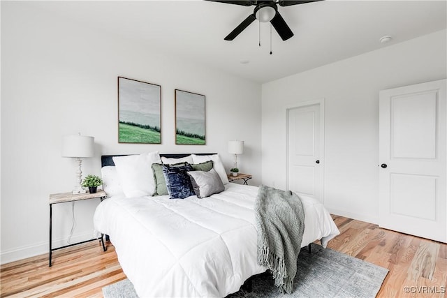 bedroom with baseboards, ceiling fan, and light wood-style flooring