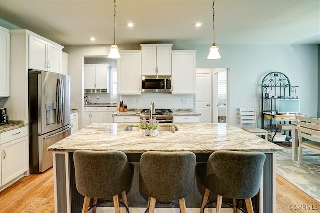 kitchen with a breakfast bar area, stainless steel appliances, and light stone countertops