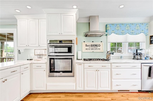 kitchen featuring ornamental molding, wall chimney exhaust hood, a wealth of natural light, and stainless steel appliances