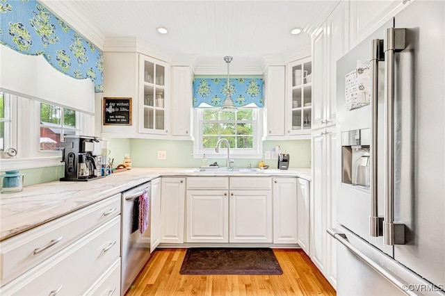kitchen featuring stainless steel dishwasher, high end refrigerator, a sink, and light wood-type flooring