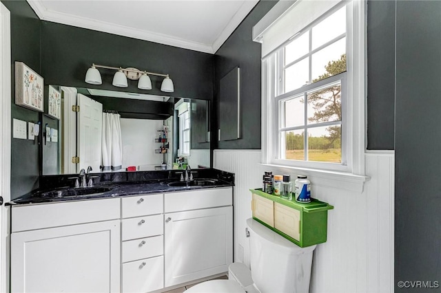 bathroom with wainscoting, toilet, ornamental molding, and a sink