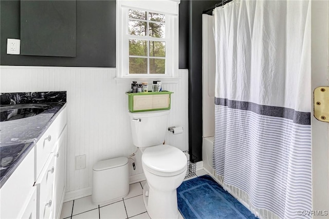 full bath with wainscoting, vanity, toilet, tile patterned floors, and a shower with curtain