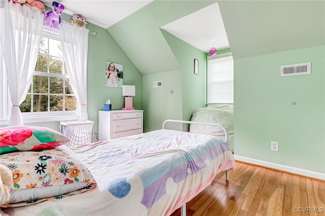 bedroom featuring baseboards, visible vents, wood finished floors, and vaulted ceiling