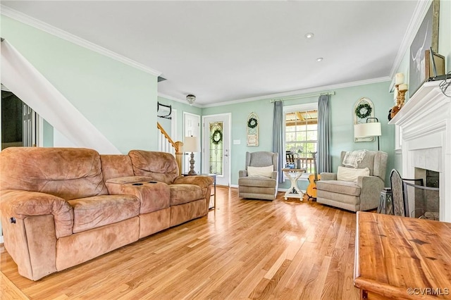 living room featuring ornamental molding, a fireplace, light wood finished floors, and stairs