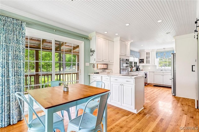 kitchen featuring appliances with stainless steel finishes, white cabinets, a peninsula, glass insert cabinets, and recessed lighting