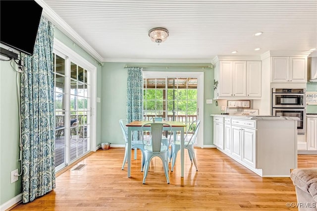 dining room featuring baseboards, ornamental molding, and light wood finished floors