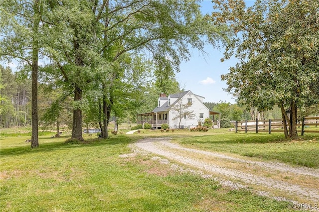 view of yard with fence and dirt driveway