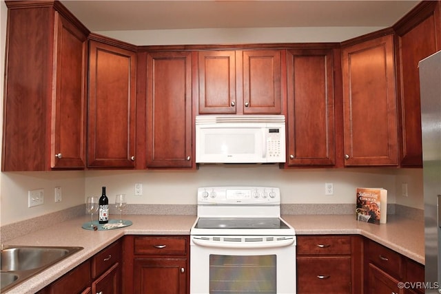 kitchen with white appliances, a sink, and light countertops