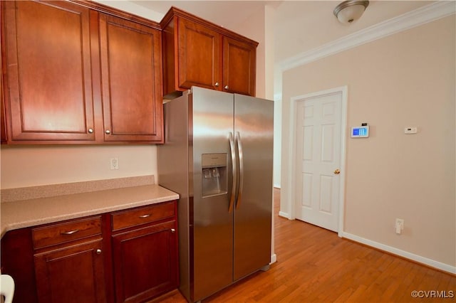kitchen featuring crown molding, light countertops, stainless steel fridge with ice dispenser, baseboards, and light wood-style flooring