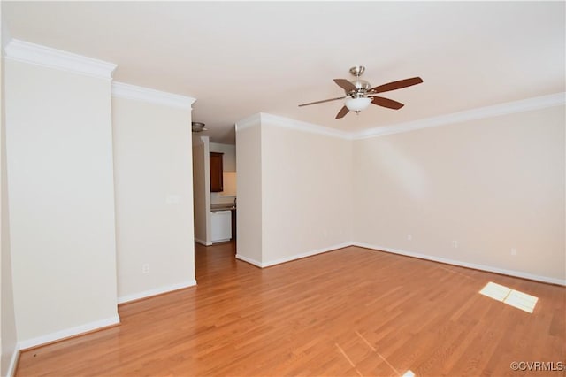 spare room featuring light wood-style floors, a ceiling fan, baseboards, and ornamental molding