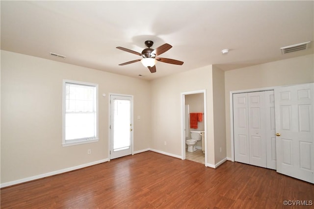 unfurnished bedroom featuring visible vents, connected bathroom, baseboards, and wood finished floors