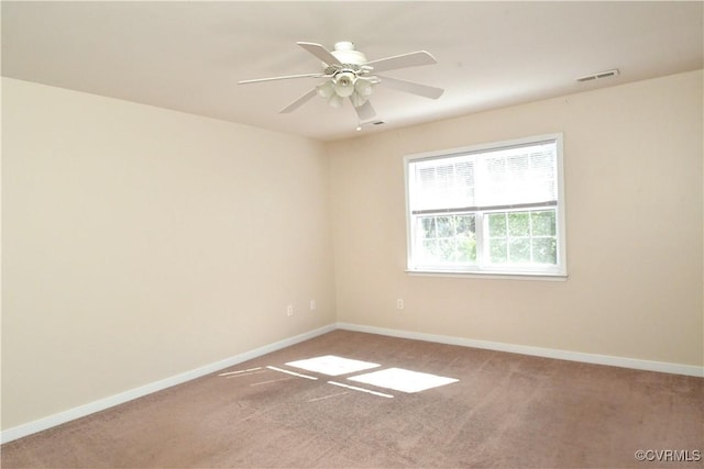 carpeted spare room featuring visible vents, a ceiling fan, and baseboards