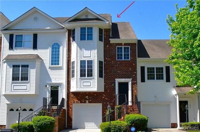 multi unit property featuring a garage, concrete driveway, and brick siding